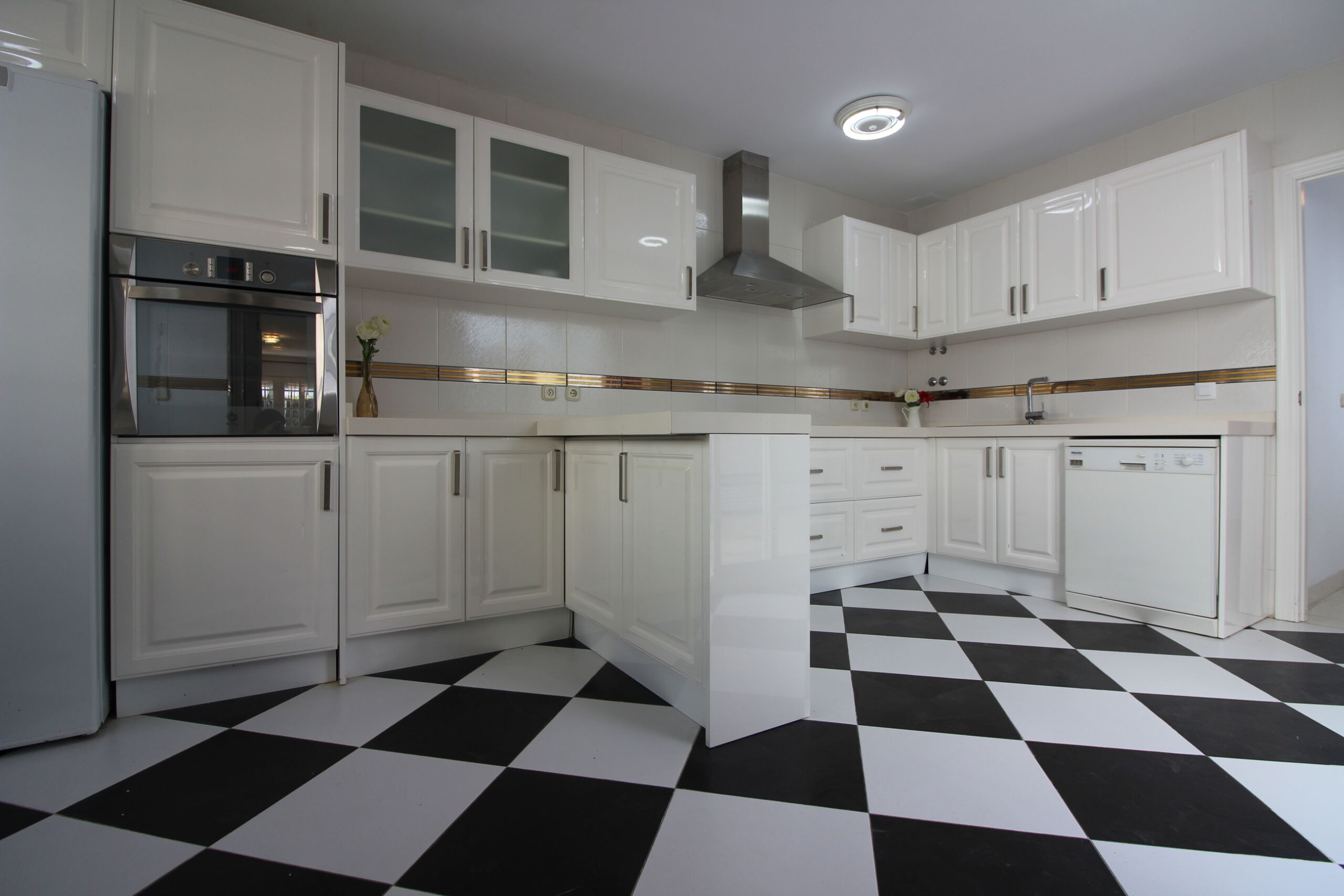 Cocina amplia de casa en venta en Rota con mobiliario blanco e isla central